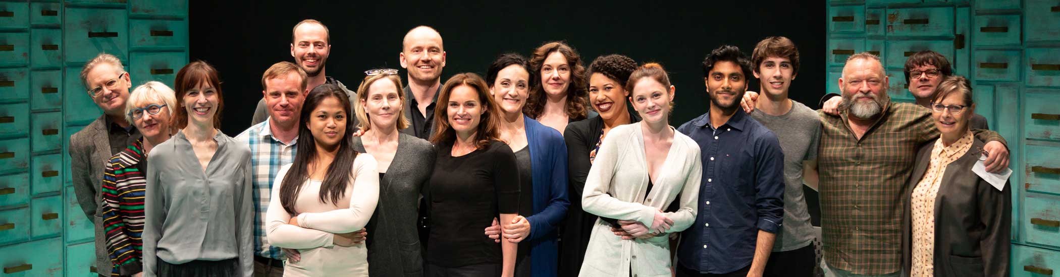 Group photo of smiling actors onstage in casual clothing.