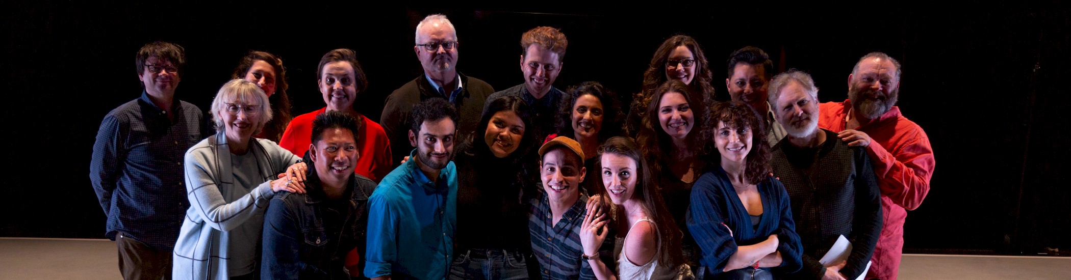 A group of eighteen actors, instructors, and staff stand together, smiling at the camera