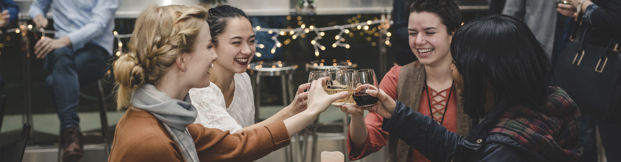 Photo of four smiling people toasting with wine glasses.