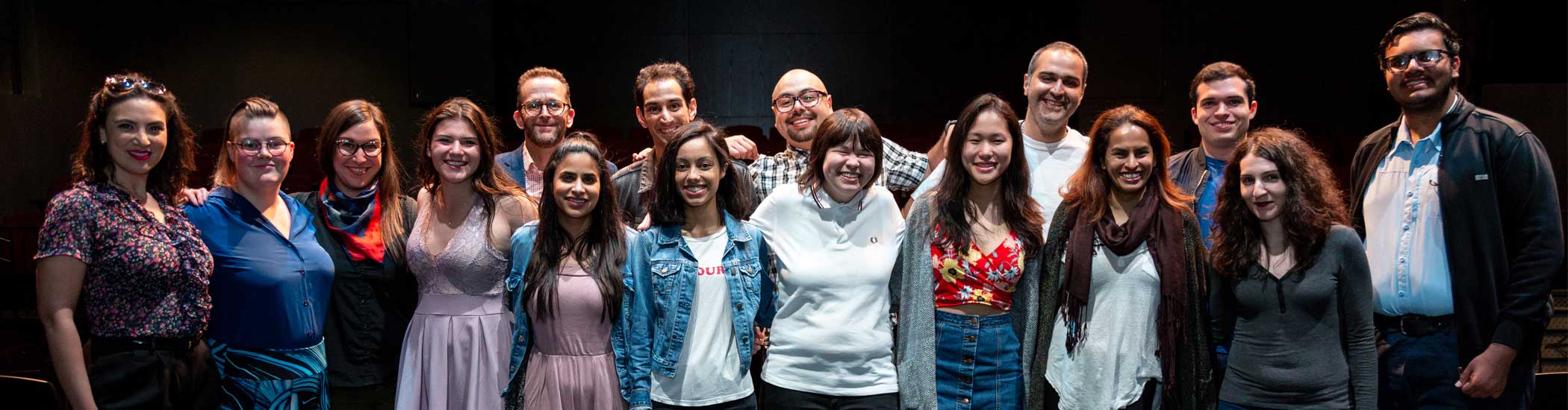 Group photo of two rows of smiling people with their arms around each other.