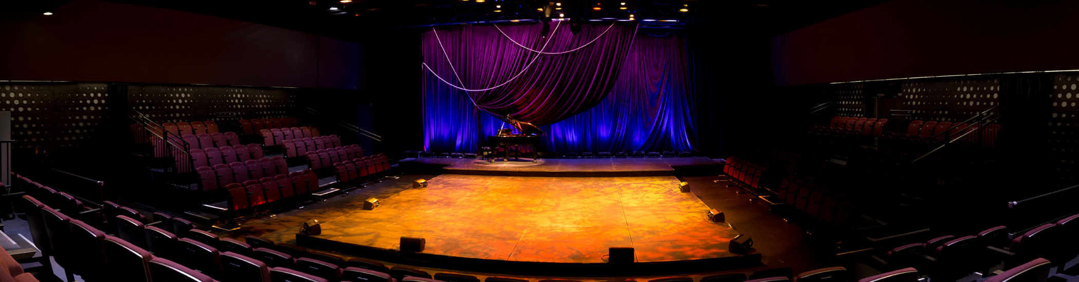 Photo of the Olympic Village Stage at the BMO theatre Centre interior. Onstage is a grand piano and the room is empty.