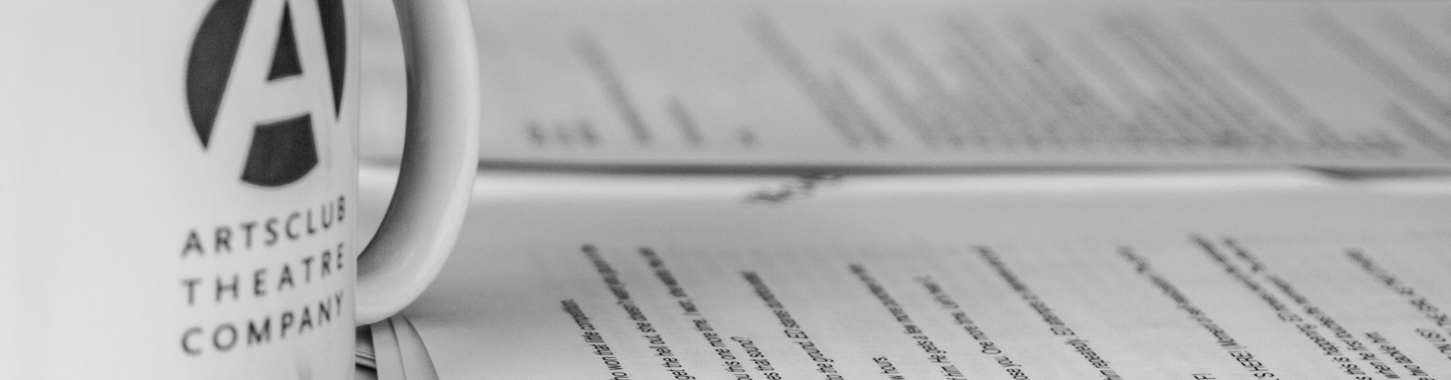 Close-up photo of a white Arts Club coffee mug and script.